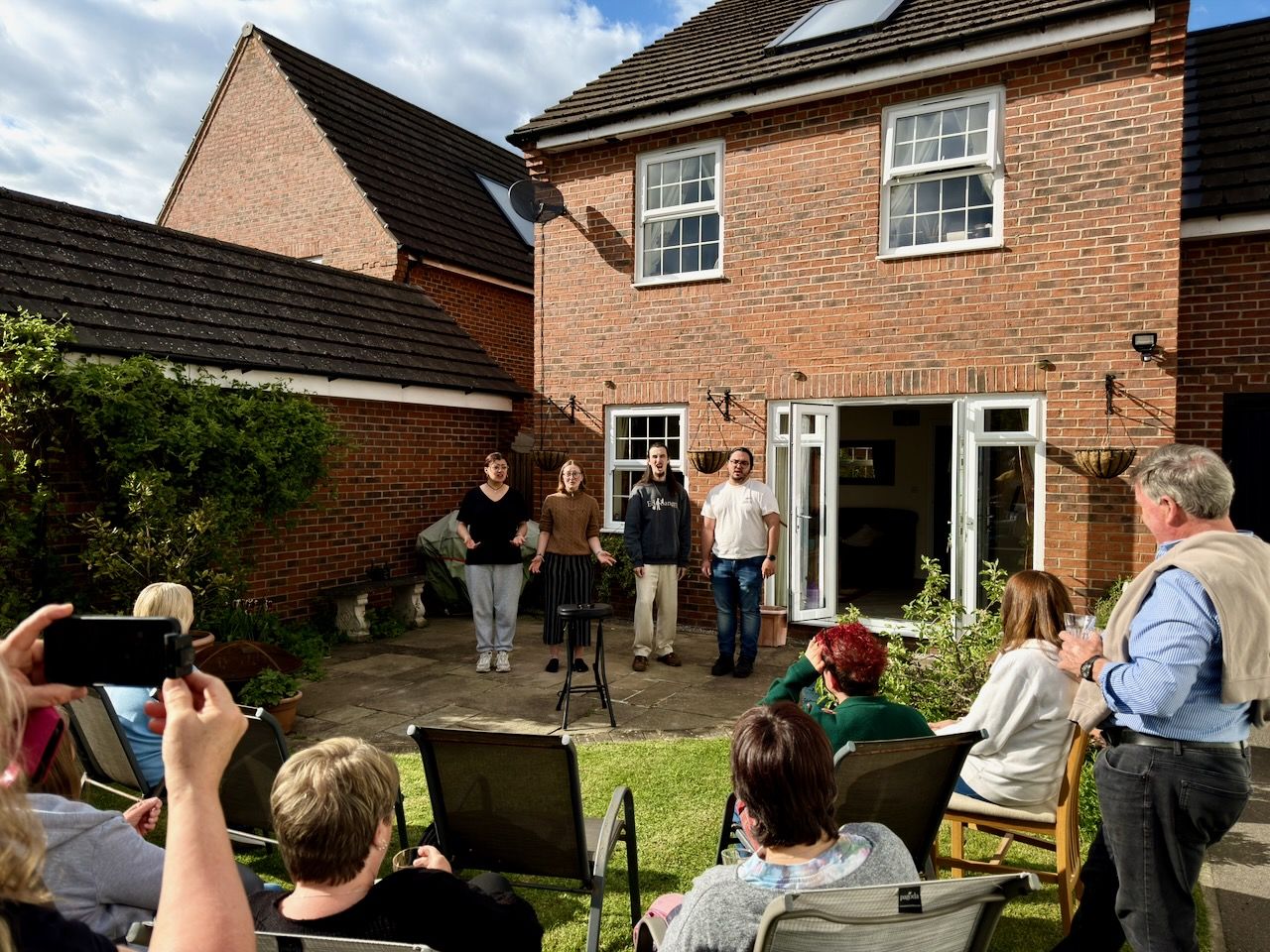A barbershop quartet singing to a small audience in a garden.